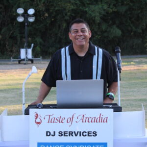 Man, John Villa, standing behind a DJ booth at the Taste of Arcadia.