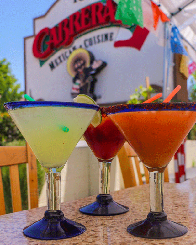 Cabrera's margaritas in blue rimmed glasses set before the Cabrera's logo