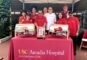 a group of people standing behind a table with a red cloth for USC Arcadia Hospital