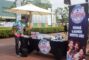 a man in a colorful shirt giving a thumbs up while standing beside a banner for comedy at the Ice House