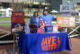 two people in blue shirts standing behind a table with a cloth reading Dave & Buster's