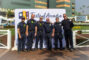 a group of men in fire fighters uniforms in front of a step and repeat banner