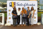 a group of women and one man in front of the Taste of Arcadia step and repeat banner and the man is holding up his arms