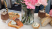 an array of savory items set with chocolate deserts in cups with a vase of pink flowers