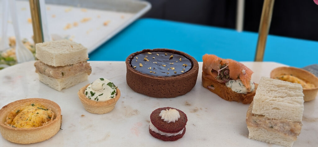 a tray set with various dessert items and sandwiches
