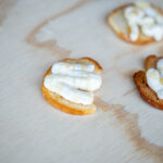 a piece of toast spread with white topping and drizzled with honey