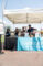 a group of people standing behind a table with a Le Meridien table cloth on it beneath a white canopy