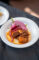 a plate of seasoned beef set on a white plate and garnished with red onions
