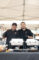 two men in black shirts and wearing black gloves standing behind a table set with chafers, and both are giving thumbs up