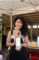 a woman with curly black hair holding up a bottle of white wine