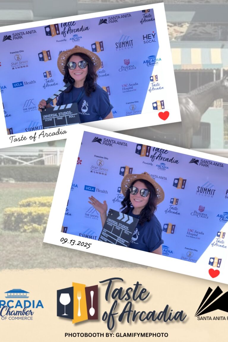 a woman in a blue Taste of Arcadia volunteer shirt and straw hat holding a clapboard in a photo booth setting with a background showing the Taste of Arcadia logo