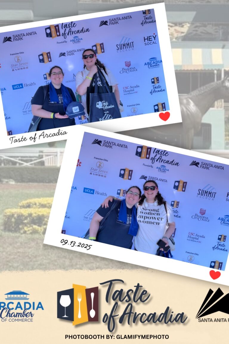 a shorter woman wearing a black t-shirt with a taller women in a white empower women shirt in a photo booth setting with a background showing the Taste of Arcadia logo