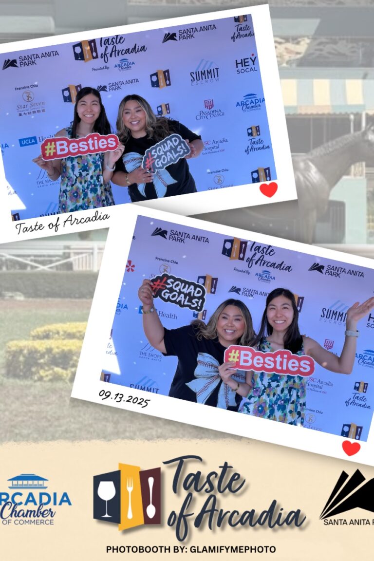 two women holding funny signs in a photo booth setting with a background showing the Taste of Arcadia logo