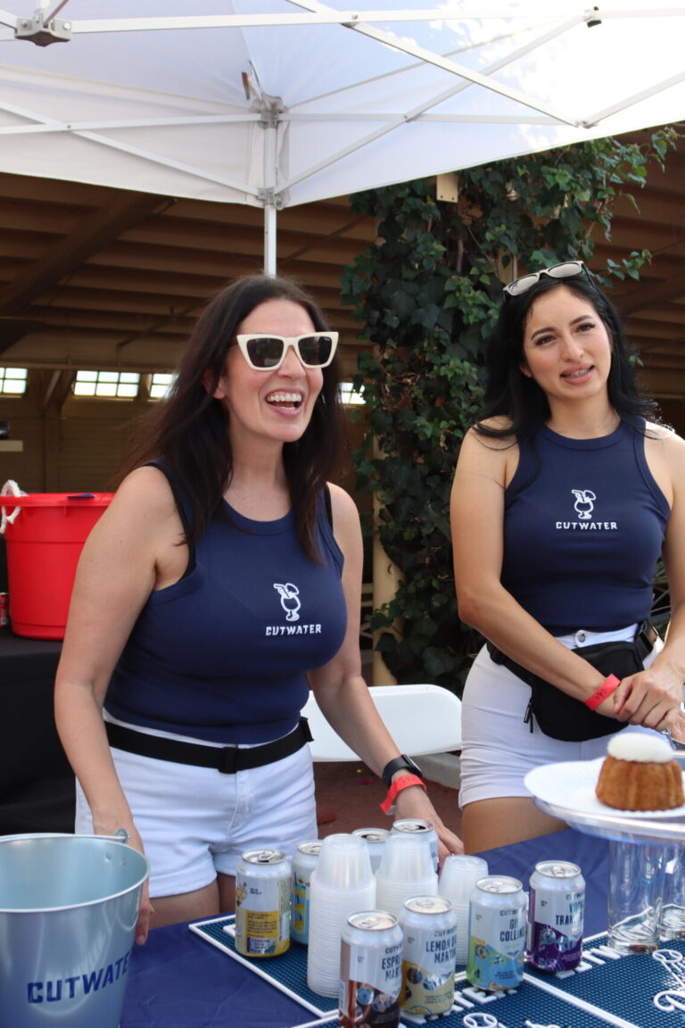 two women wearing Cutwater shirts behind a booth of drinks