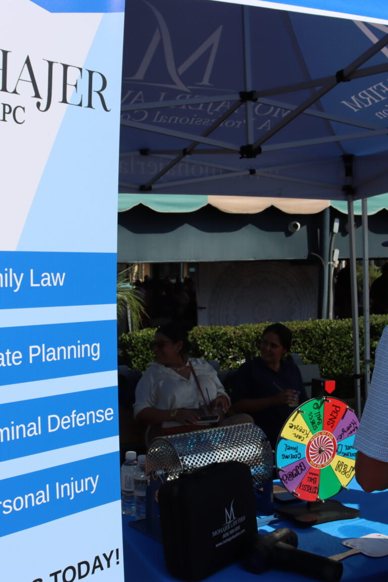 a glimpse of the Mohajer Law business booth beside a banner showing Sina Mohajer