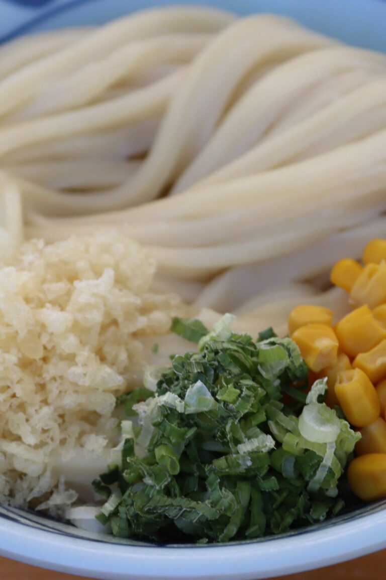 a bowl of udon noodles with corn and other toppings