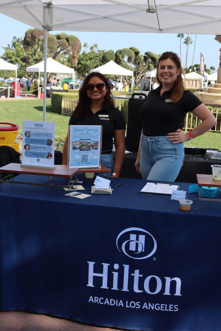 two women stand behind a booth for Hilton Arcadia