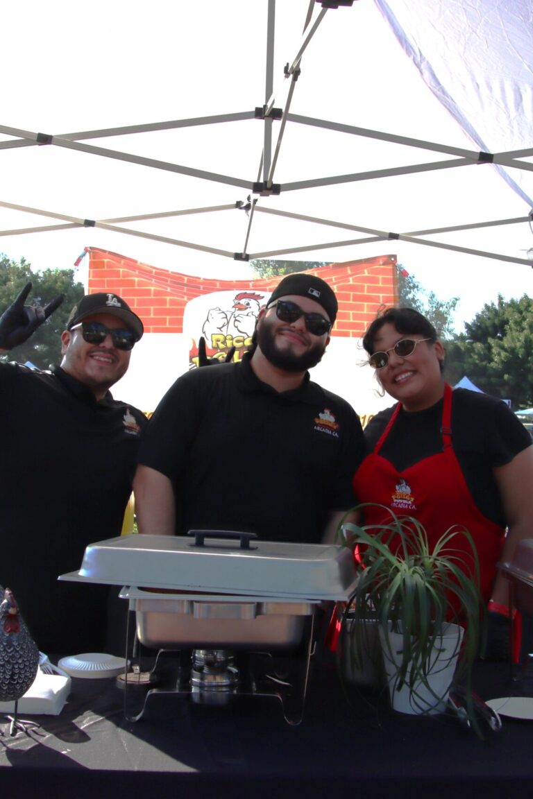 two men behind a booth for Rico's Pollo at Taste of Arcadia