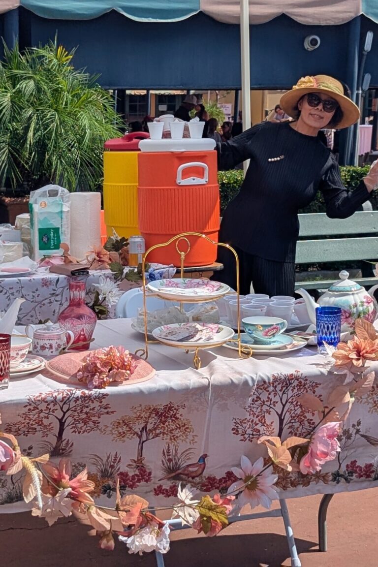 a woman waving at the camera at a booth for Rose Angel Tea House at Taste of Arcadia