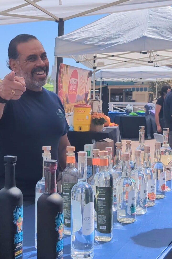a man pointing at the camera at a booth for Aguirre Tequila at Taste of Arcadia