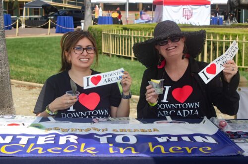 two women wearing I love Downtown Arcadia shirts holding up I love Downtown Arcadia bumper stickers