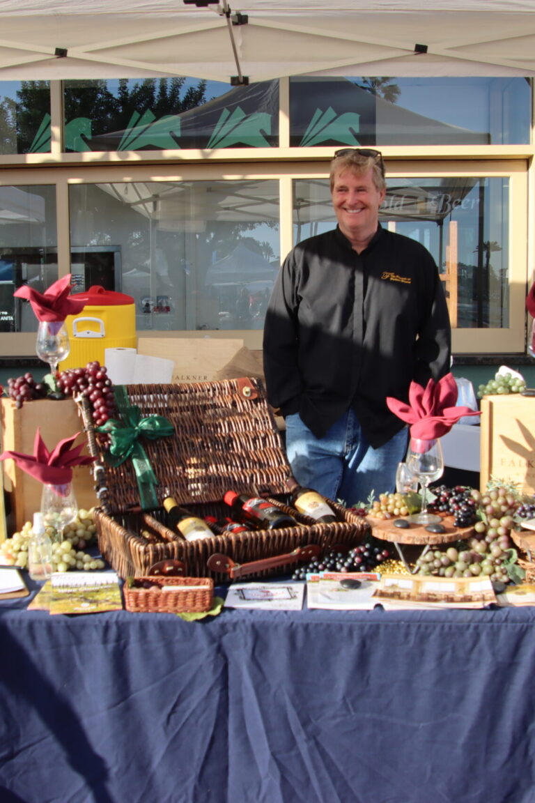 a man behind a decorated booth for Falkner wines at Taste of Arcadia