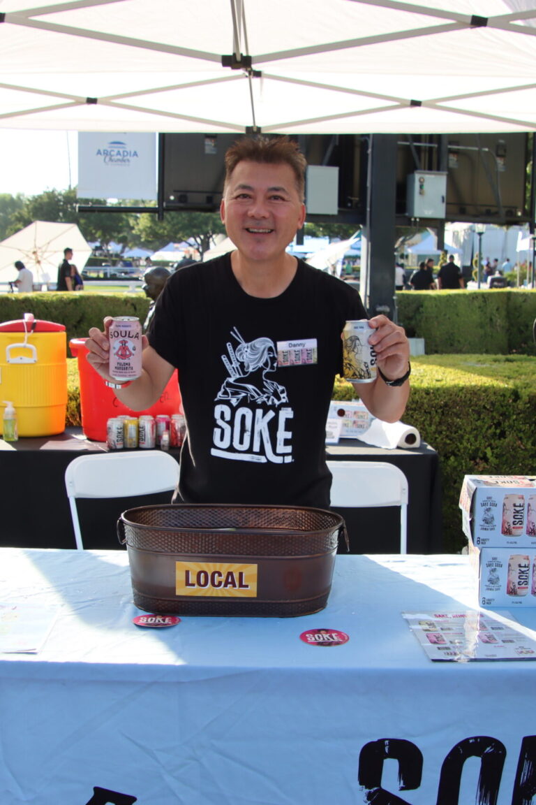 a man holding up two cans of Sake for a Spirited Brands booth at Taste of Aracdia