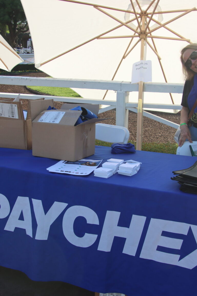 a woman standing behind a booth for Paychex at Taste of Arcadia