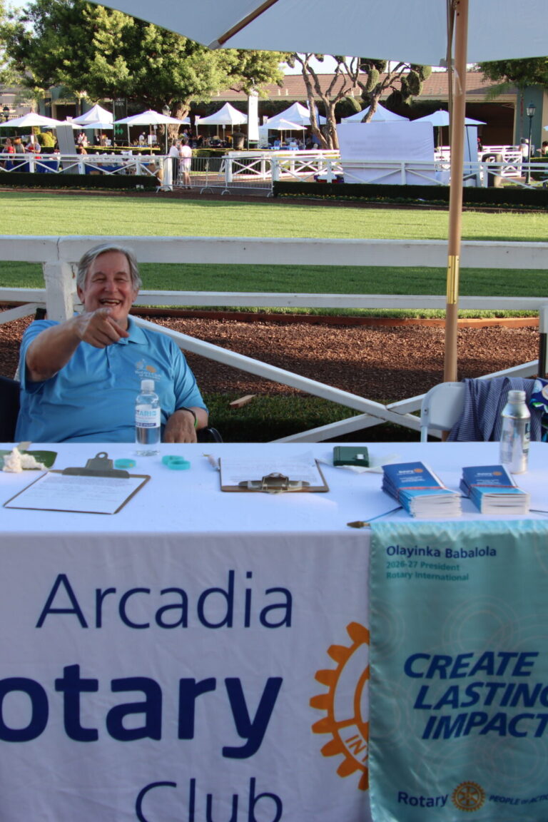a man at the Arcadia Rotary Booth pointing at the camera and smiling, at Taste of Arcadia