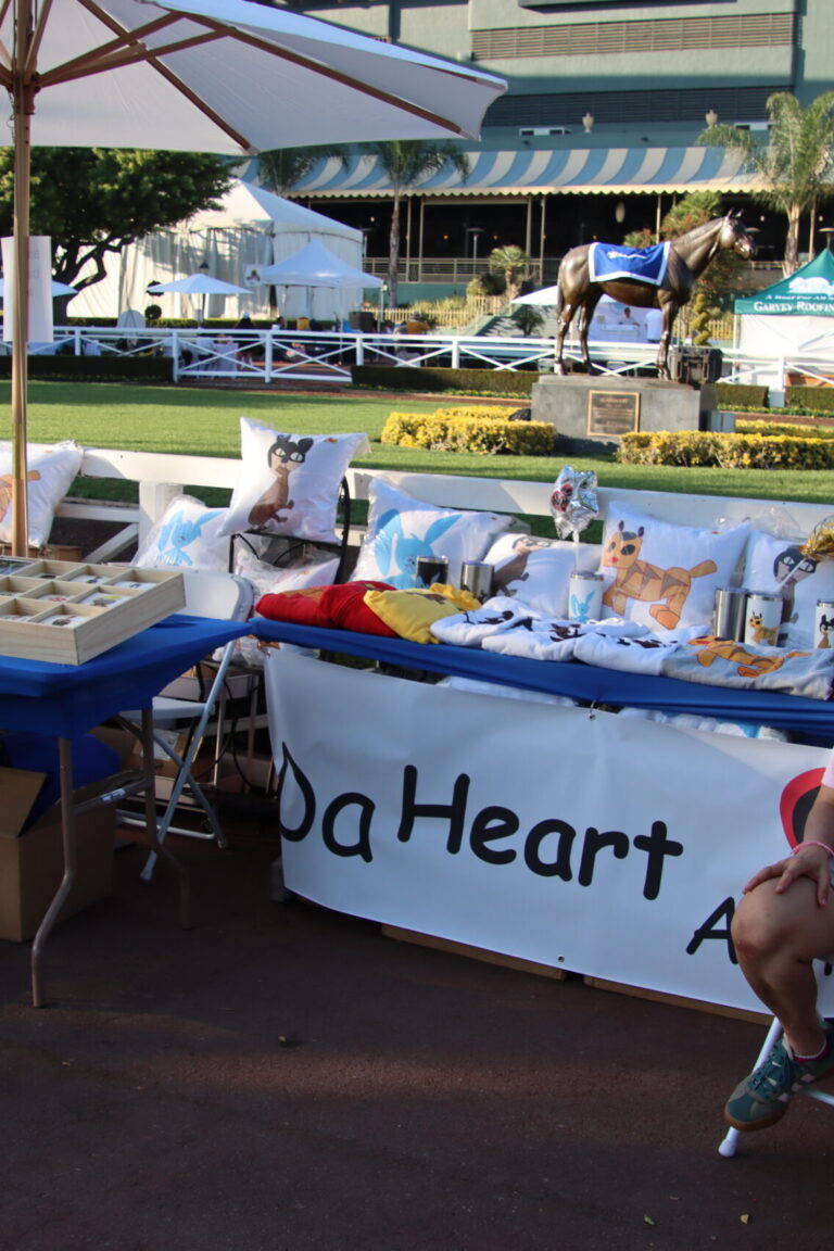a woman seated by a booth for Da Heart Anime at Taste of Arcadia