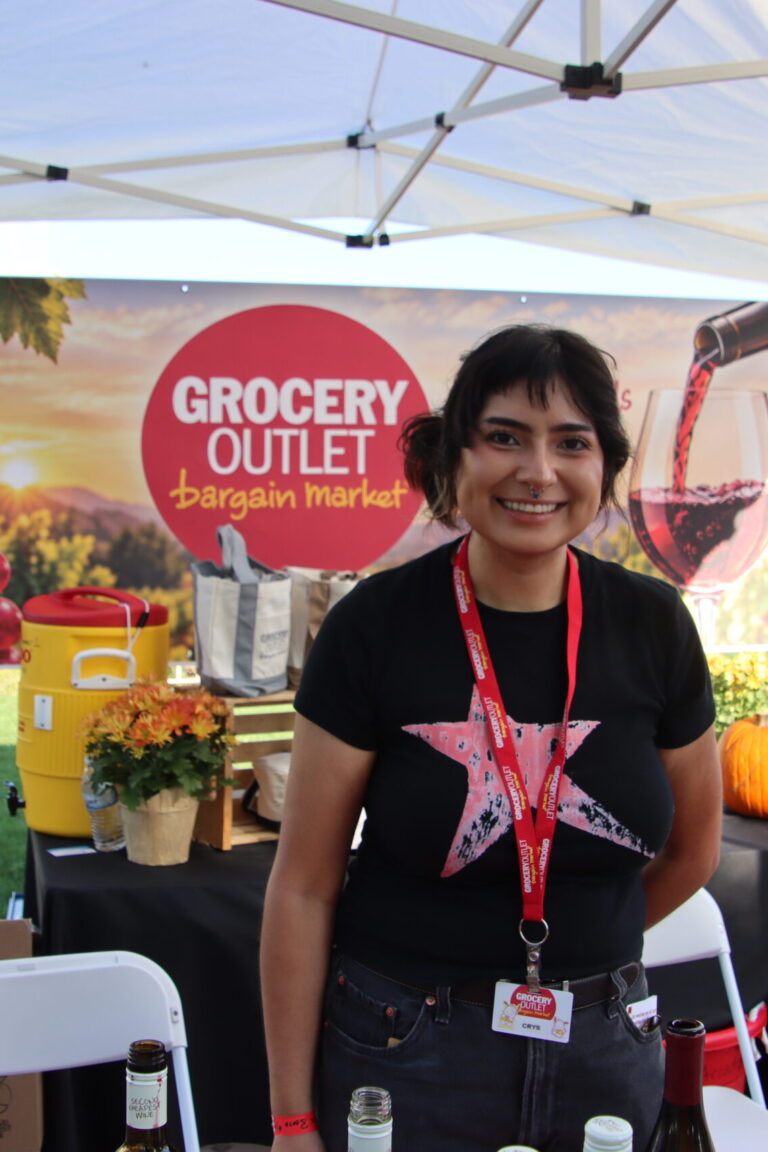 a woman in a black t-shirt with a red star on it behind a booth Grocery Outlet at Taste of Arcadia