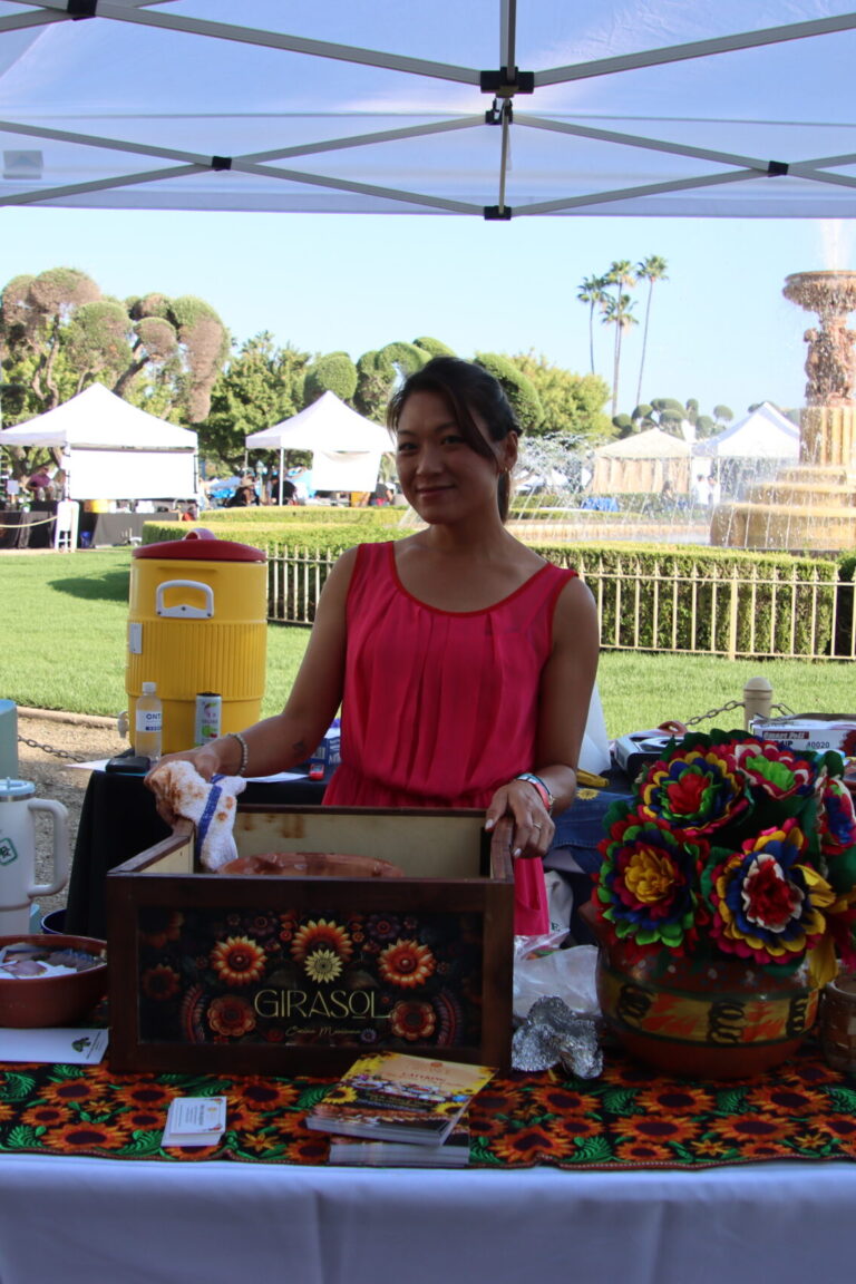a woman in a pink shirt behind a booth for Girasol at Taste of Arcadia