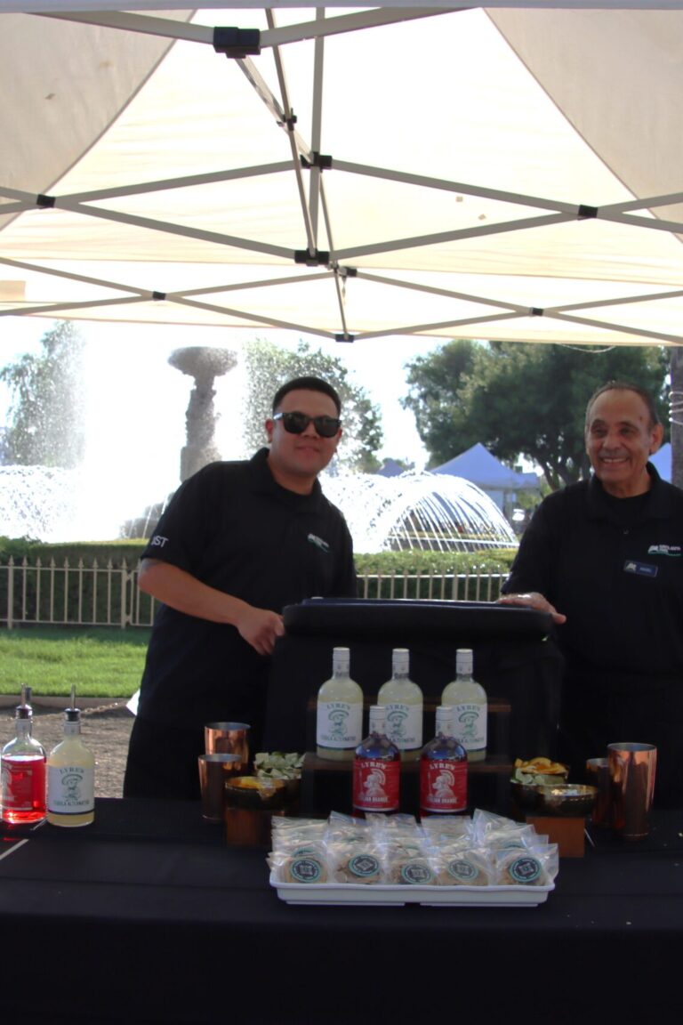 two men stand behind a booth for Santa Anita Park at Taste of Arcadia
