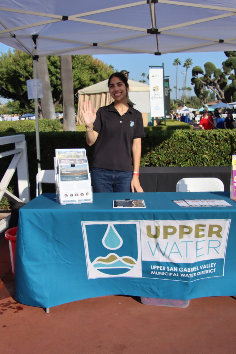 a woman standing at a booth set with Upper Water items at Taste of Arcadia