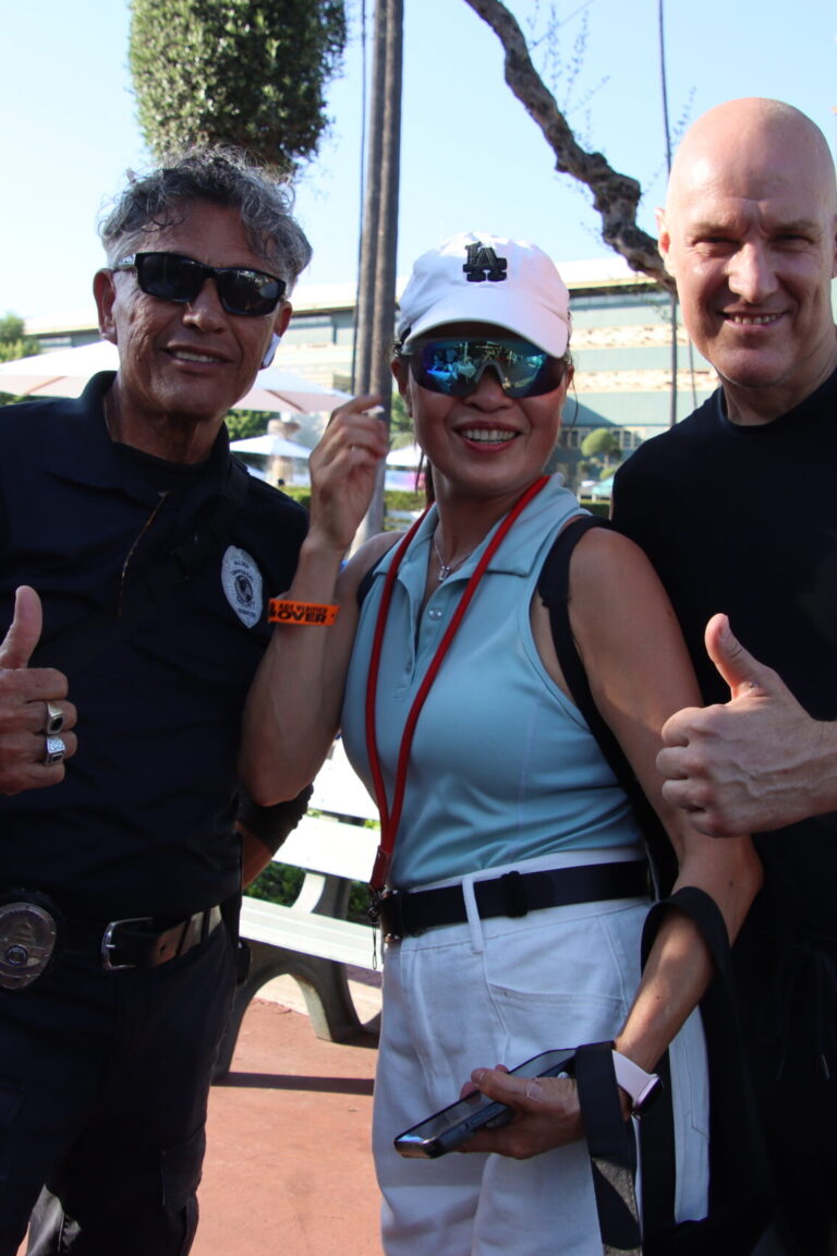 a woman in a blue shirt standing between two men who are giving thumbs up