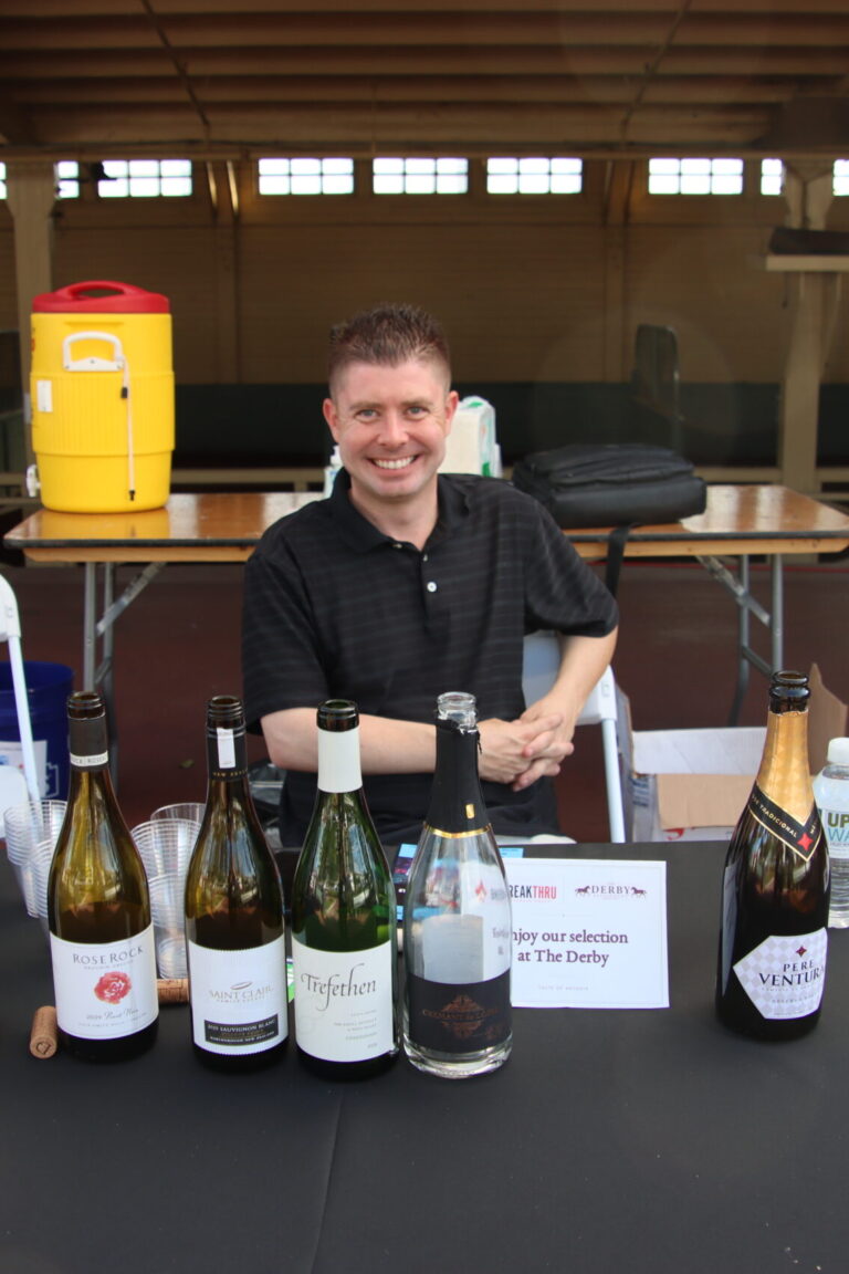 a man seated behind a booth set with wine bottles from Breakthru at Taste of Arcadia