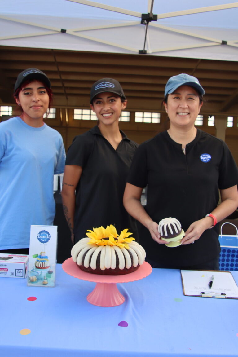 three women standing behind a table set with a bundt cake from Nothing Bundt Cakes at Taste of Arcadia