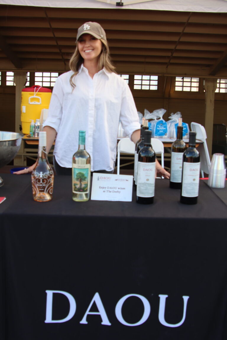 a woman in a white shirt behind a booth that says Daou at Taste of Arcadia
