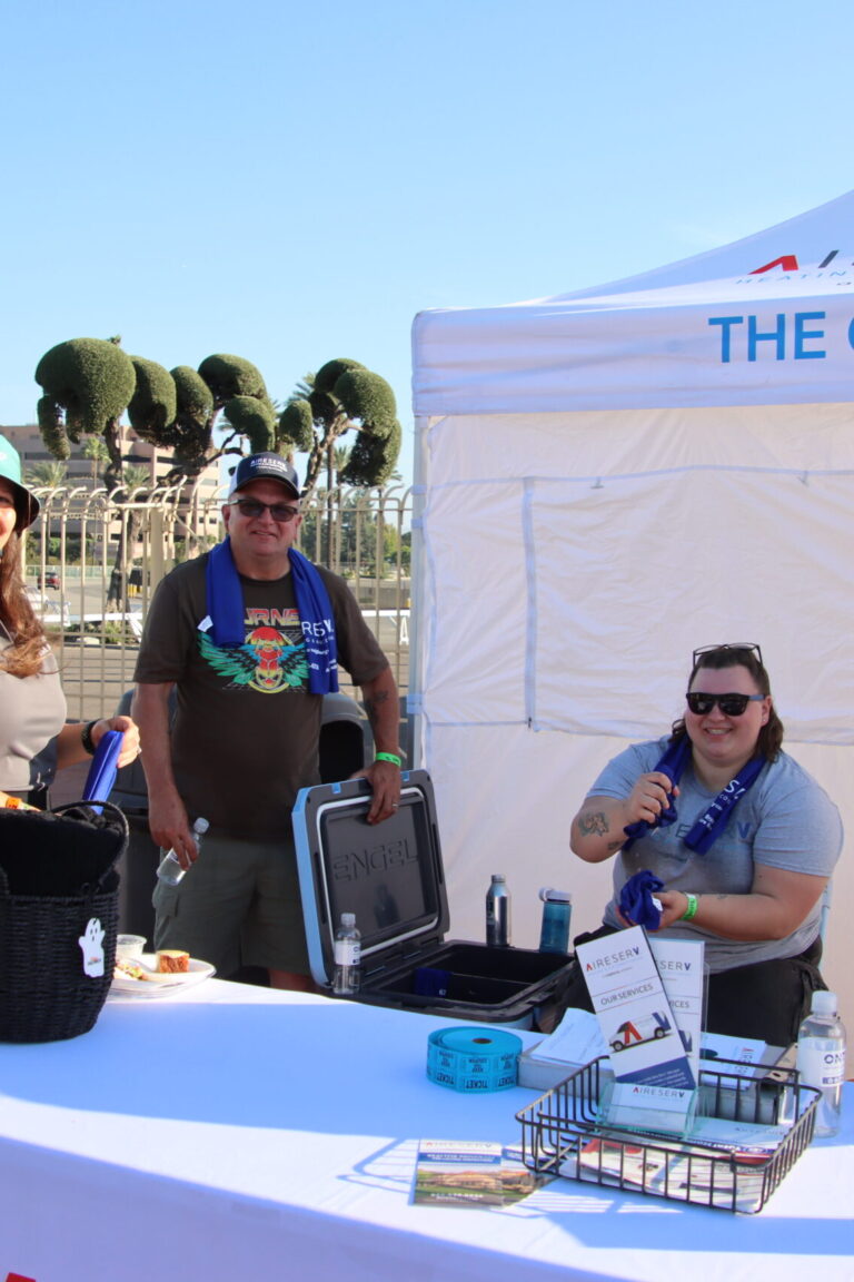 a group of people standing in front of a cooling tent from Aire Serv at Taste of Arcadia